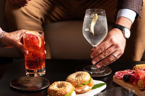 a person holding a drink next to a table with food at Phi Hotel Canalgrande in Modena