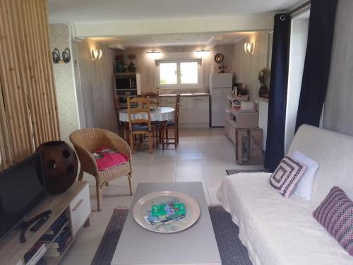 a living room with a white couch and a table at Appartement Pont l'Abbé Entre océan et campagne in Pont-lʼAbbé