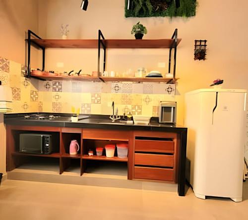 a kitchen with a counter with a sink and a refrigerator at Laguna Lofts in Poços de Caldas