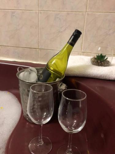 a bottle of wine in a bucket next to two wine glasses at 3 Beds Urban Escape Home in Gaborone