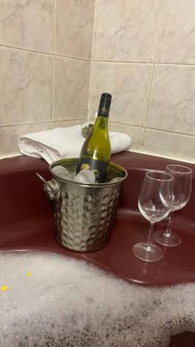 a bottle of champagne and two glasses on a bath tub at 3 Beds Urban Escape Home in Gaborone