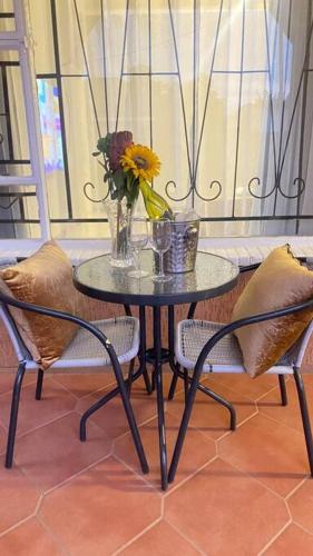a table with a vase of flowers and two chairs at 3 Beds Urban Escape Home in Gaborone