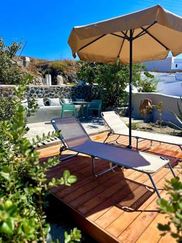 a patio with two chairs and an umbrella at Okeanos Suite 1, Panoramic sea &garden view in Foinikiá