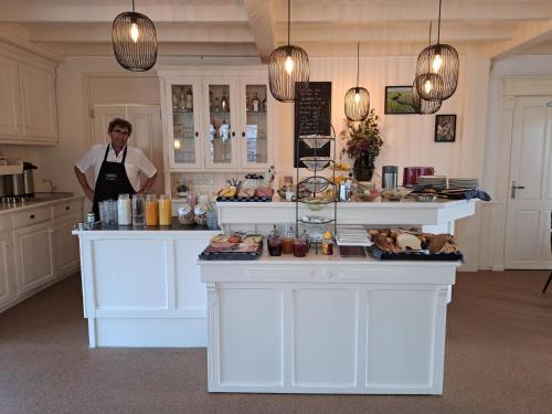 a man standing behind a counter in a kitchen at Hotel Het Gouden Boltje in De Koog