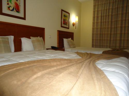 a hotel room with two beds with white sheets at Hotel Pombeira in Guarda