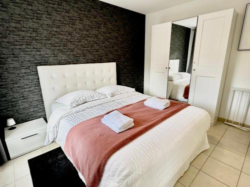 une chambre avec un grand lit avec deux serviettes dessus dans l'établissement Le Cubry : Appart hyper-centre avec une place de parking, à Épernay