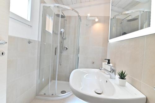 a white bathroom with a shower and a sink at IzzHome The Breeze in Cagliari