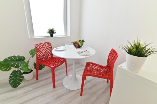 a white table with two red chairs and a white table at IzzHome The Breeze in Cagliari