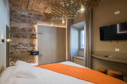 a bedroom with a bed with an orange blanket and a tv at 163 BOUTIQUE HOTEL in Rome