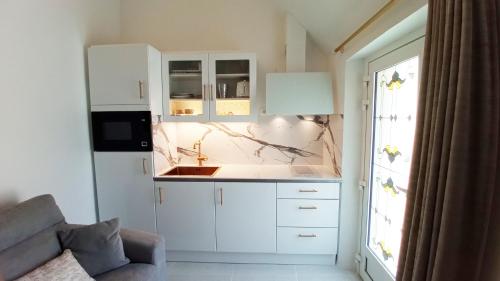 une cuisine avec des armoires blanches et un évier dans l'établissement D-DAY's, à Bayeux