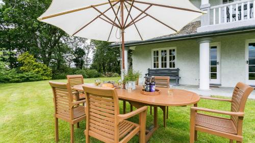 a wooden table and chairs with an umbrella at Hafod Cae Maen in Penrhyndeudreath