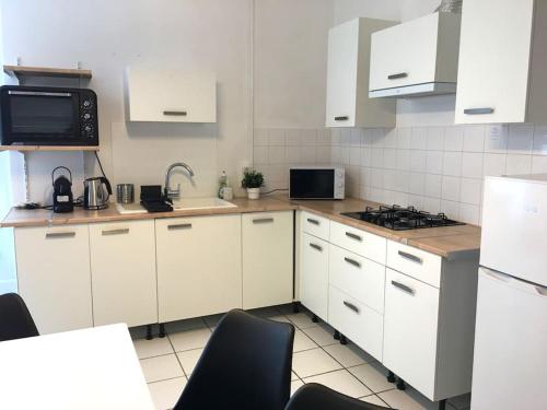 a kitchen with white cabinets and a sink and a microwave at Très grand appartement ancien avec petit jardin in Nevers
