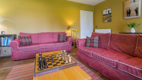 a living room with two red couches and a chess board at Hafod Cae Maen in Penrhyndeudreath