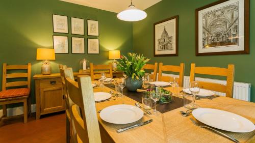 a dining room with a wooden table and green walls at Hafod Cae Maen in Penrhyndeudreath