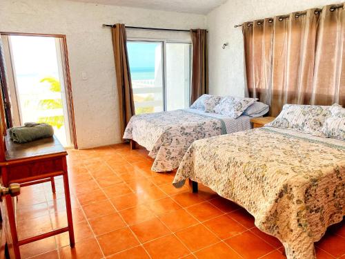 a hotel room with two beds and a window at Casa Saltwater Cowboy En La Playa - Beachfront Property in Chuburná