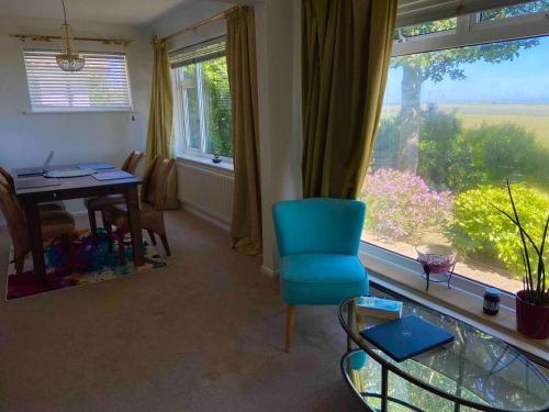 a living room with a blue chair and a table and a window at House - Free Parking & Sea Views in Brighton & Hove