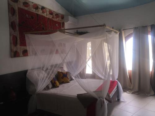 a bedroom with a bed with a mosquito net at Warang plage villa in Mbour