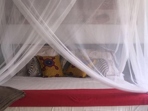 a bed with white curtains and pillows on it at Warang plage villa in Mbour