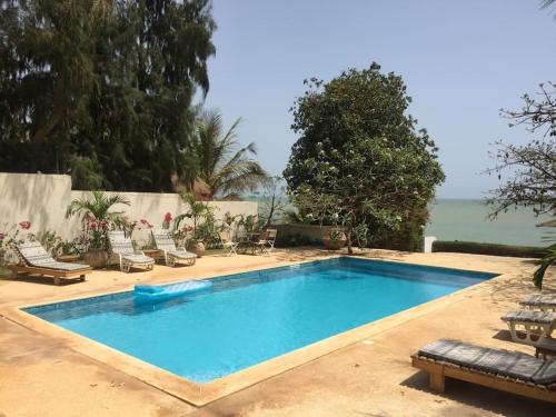 a swimming pool with chairs and the ocean in the background at Warang plage villa in Mbour