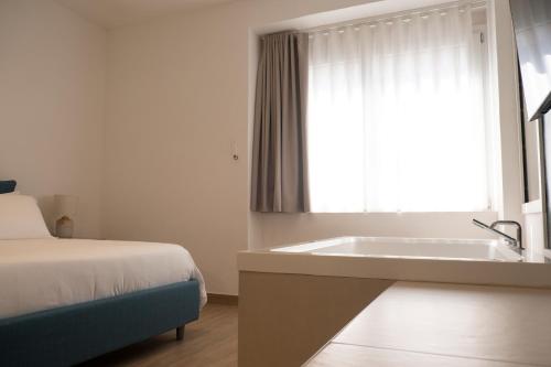 a bedroom with a bed and a bath tub next to a window at Monumental Luxury Rooms in Caserta