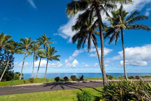 a road with palm trees and the ocean in the background at Hanalei Bay Villa 26 in Princeville