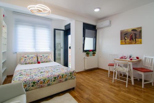 a white bedroom with a bed and a table at Gracija in Jagodina