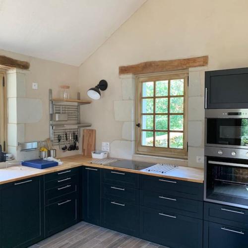 une cuisine avec des armoires bleu foncé et une fenêtre dans l'établissement Charmante maison en Touraine, entre champs et châteaux, à Razines