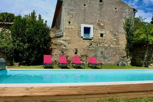 - un groupe de chaises roses assis à côté d'une piscine dans l'établissement Le Cerisier at Closerie Les Roches - 2 Bed Country Cottage, à Bouillé-Loretz
