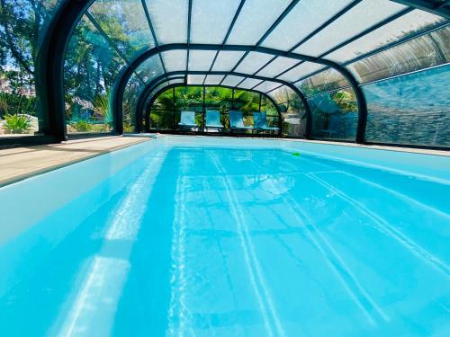 une piscine intérieure avec un toit en verre dans l'établissement Love room avec jacuzzi intérieur proche Blagnac, à Aussonne