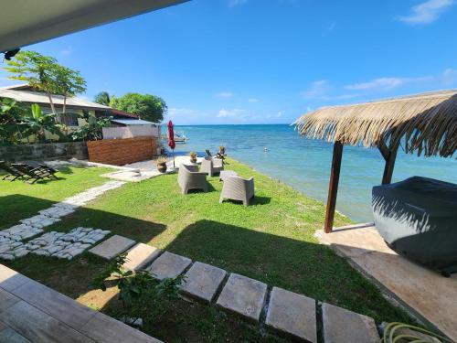 a lawn with chairs and a view of the ocean at Studio bord de mer Fare Tahitea Pension in Taputapuapea