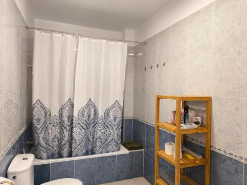 a bathroom with a shower curtain and a toilet at Acogedoras Habitaciones Privadas zona Costera Wifi in Morro del Jable