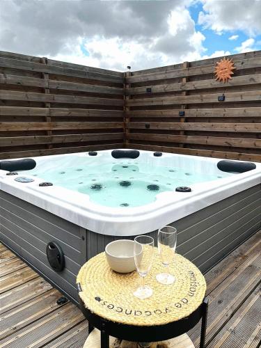 un bain à remous sur une terrasse avec une table avec des verres à vin dans l'établissement Cottage in Premium residence in Sainte-Foy, à Sainte-Foy