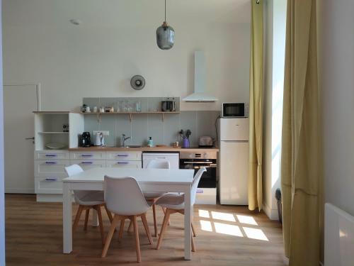 une cuisine blanche avec une table et des chaises blanches dans l'établissement La Noisille - Cité médiévale, à Gourdon
