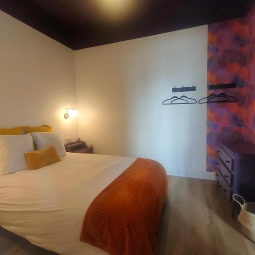 - une chambre dotée d'un grand lit blanc et d'une peinture murale dans l'établissement La Noisille - Cité médiévale, à Gourdon