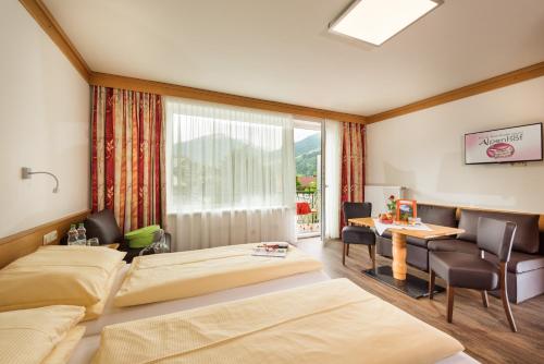 バート・ホーフガシュタインにあるホテル アルペンホフのベッド2台とテーブルが備わるホテルルームです。