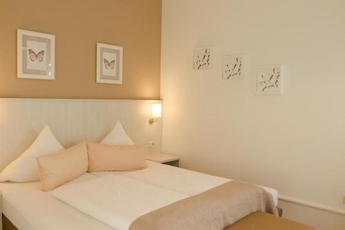 a bedroom with a white bed and some pictures on the wall at Hotel Luise in Bad Bergzabern