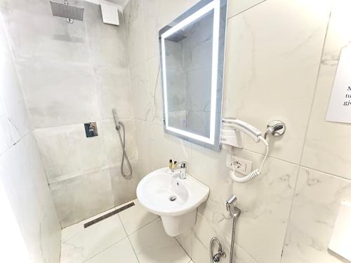 a white bathroom with a sink and a shower at Tirana Square Hotel in Tirana