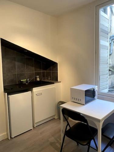 une cuisine avec une table blanche et un four micro-ondes. dans l'établissement Studio Nancy Centre-Gare !, à Nancy