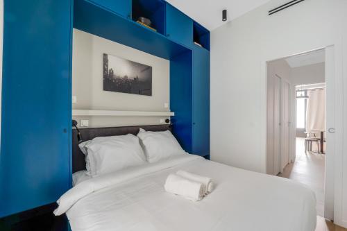 - une chambre bleue avec un grand lit et des oreillers blancs dans l'établissement Magnifique Appartement Paris XVIIe-Tout équipé!, à Paris