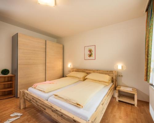 a bedroom with a large bed with a wooden headboard at Hotel Alpenhof - New Sauna Area in Bad Hofgastein