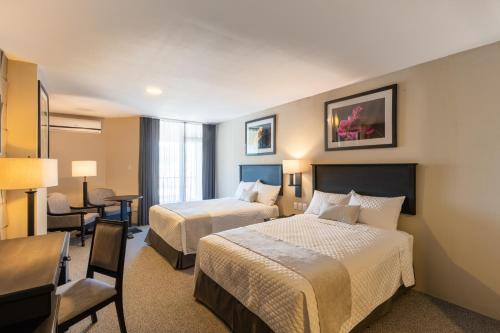 a hotel room with two beds and a desk at Conquistador Hotel & Conference Center in Guatemala