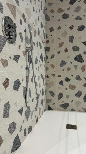 a shower in a bathroom with a patterned wall at Boca Luxury Rooms in Tarquinia