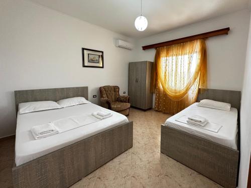 a bedroom with two beds and a chair and a window at Vila Jeti in Ksamil
