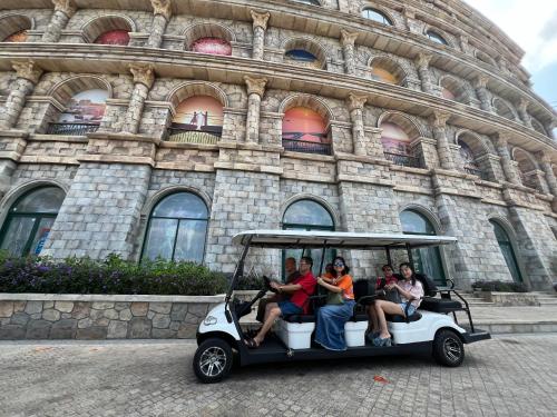 a group of people riding a golf cart in front of a building at Oscar Seaview Apartment in Phu Quoc