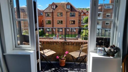 an open window with a view of a brick building at HighTide - 2 bed with parking, balcony & sea view. in Swanage