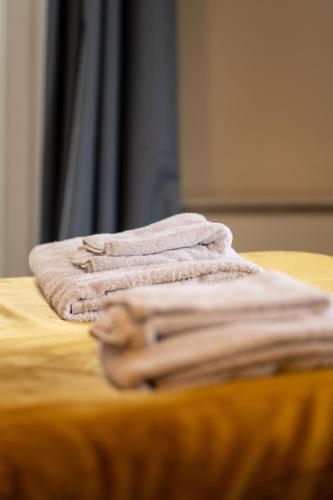 a pile of towels sitting on top of a bed at Aryas Apartments Oxford - Headington in Oxford