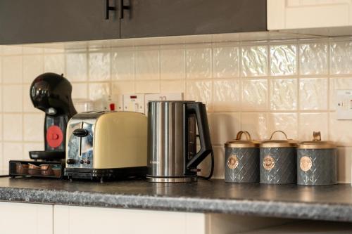 a kitchen counter with a toaster and cups on it at Aryas Apartments Oxford - Headington in Oxford