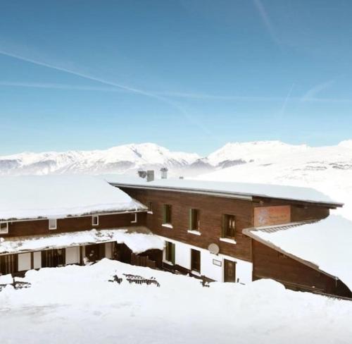 a building covered in snow with mountains in the background at Peisey Vallandry, L'appartement au pied des pistes in Landry
