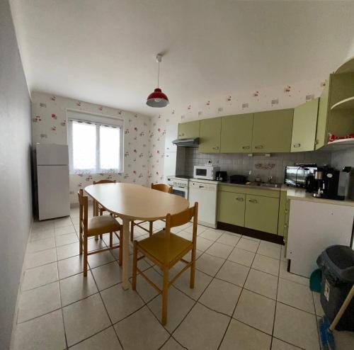 une cuisine avec des armoires vertes, une table et des chaises dans l'établissement Maison de famille, à Sainte-Mère-Église