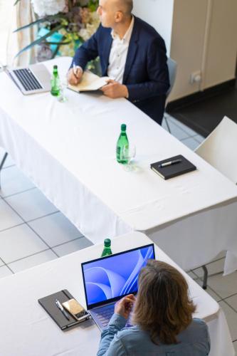 a man in a suit sitting at a table with a laptop at Villa-des-eaux Claires in Puymoyen